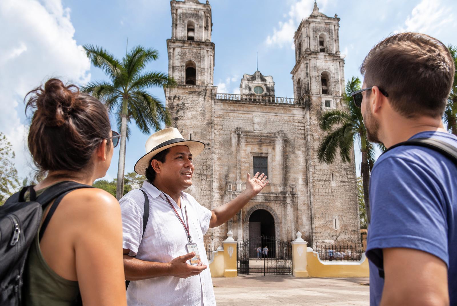 Guía local explicando la catedral de Valladolid a dos viajeros